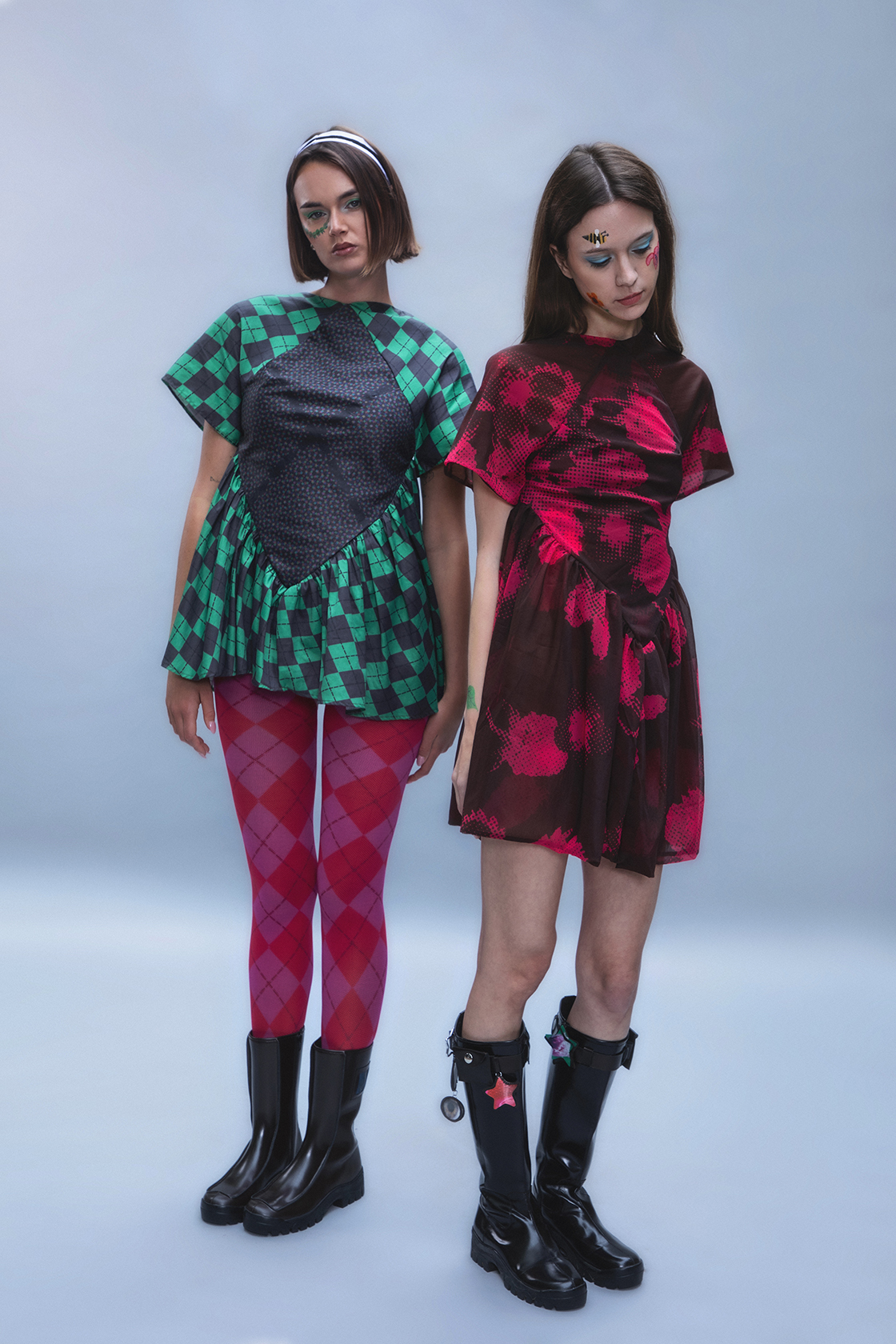 Full body shot of two models in colorful clothes next to each other posing serenly against a gray backdrop